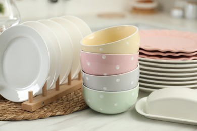 Photo of Clean plates, bowls and butter dish on white marble table in kitchen