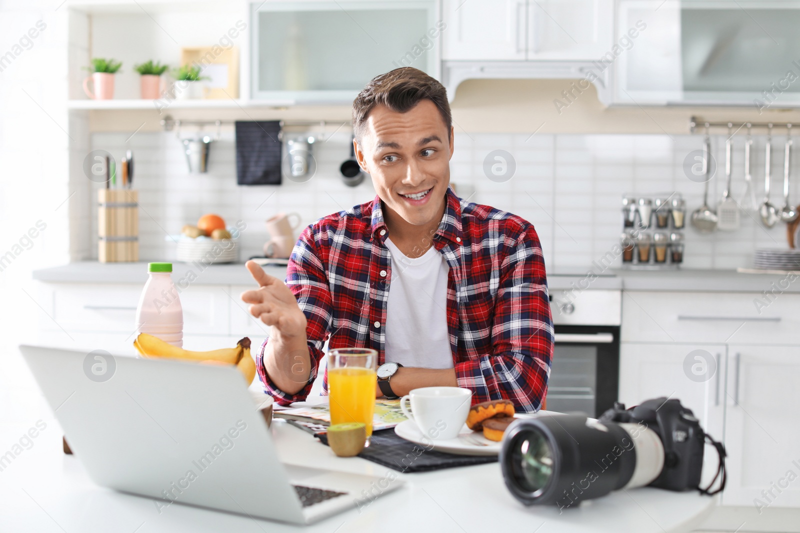 Photo of Portrait of food blogger with laptop and camera in kitchen. Online broadcast