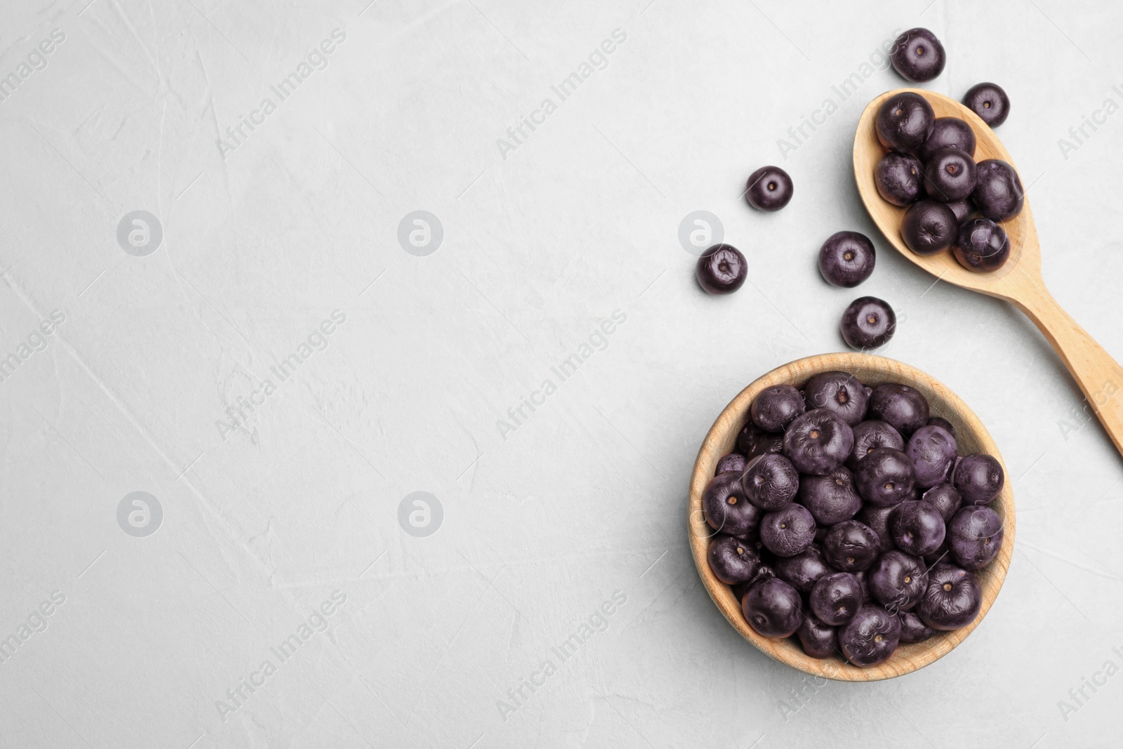 Photo of Flat lay composition with fresh acai berries on light stone table, space for text