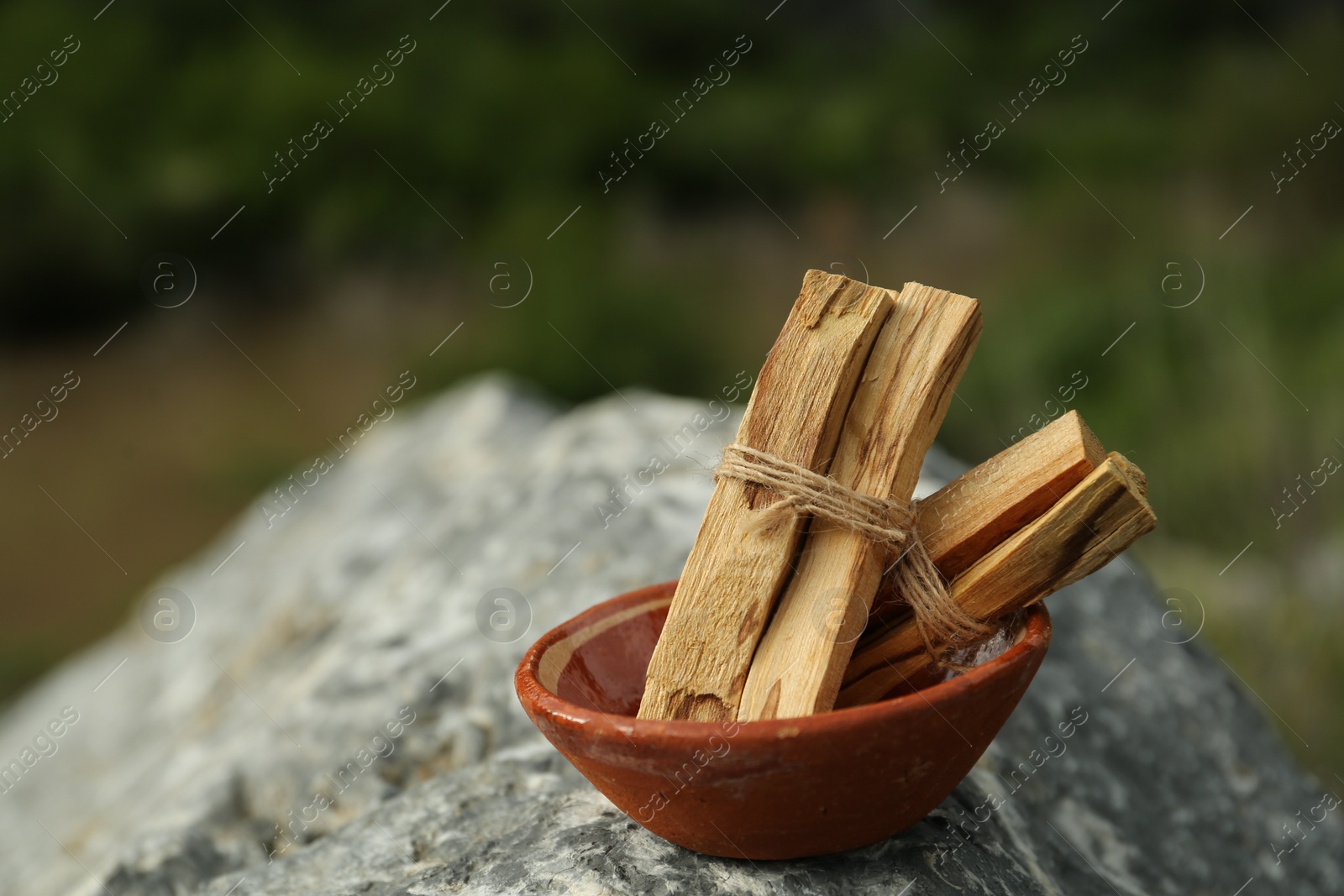 Photo of Many palo santo sticks on stone surface outdoors, closeup. Space for text