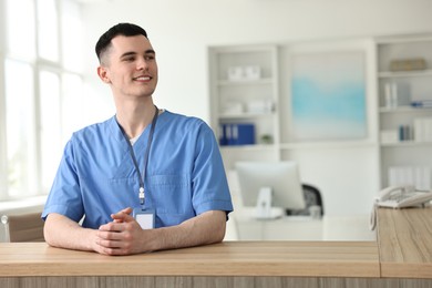 Photo of Smiling medical assistant at hospital reception. Space for text