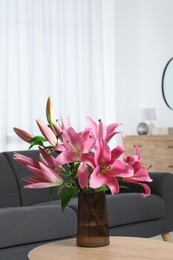 Beautiful pink lily flowers in vase on wooden table indoors, space for text