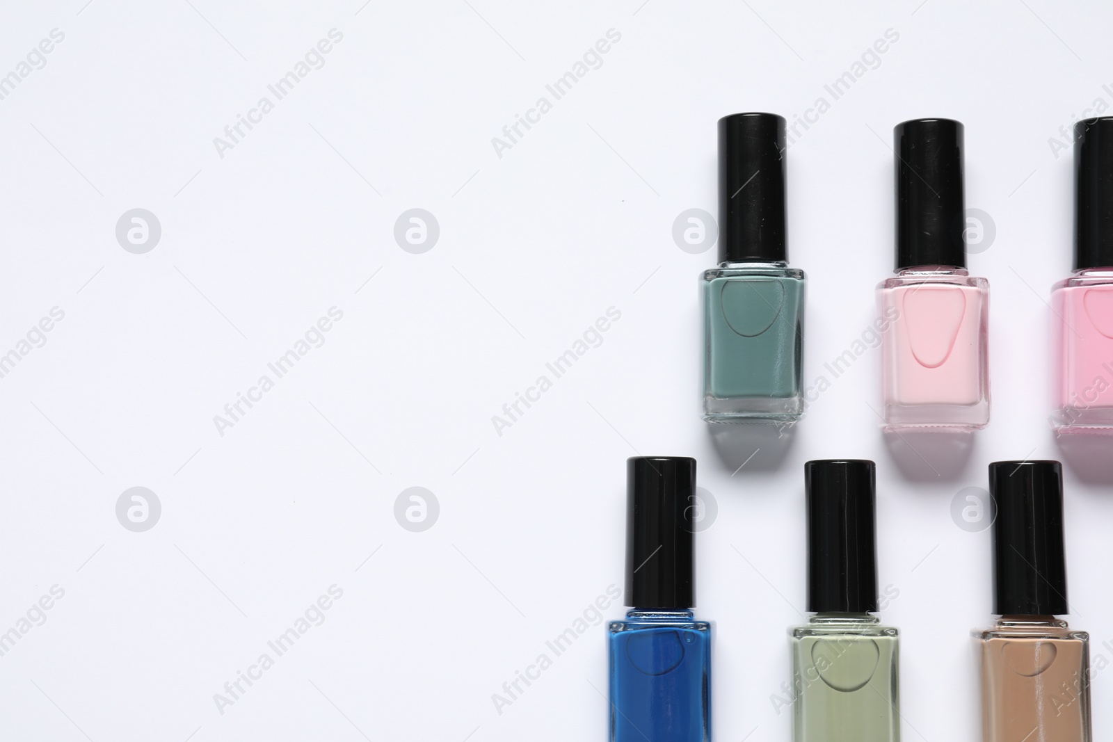 Photo of Nail polishes on white background, flat lay. Space for text