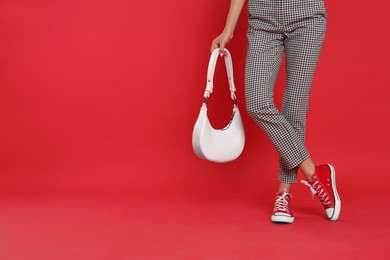 Photo of Woman with stylish bag on red background, closeup. Space for text