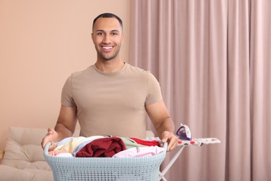 Happy man with basket full of laundry at home