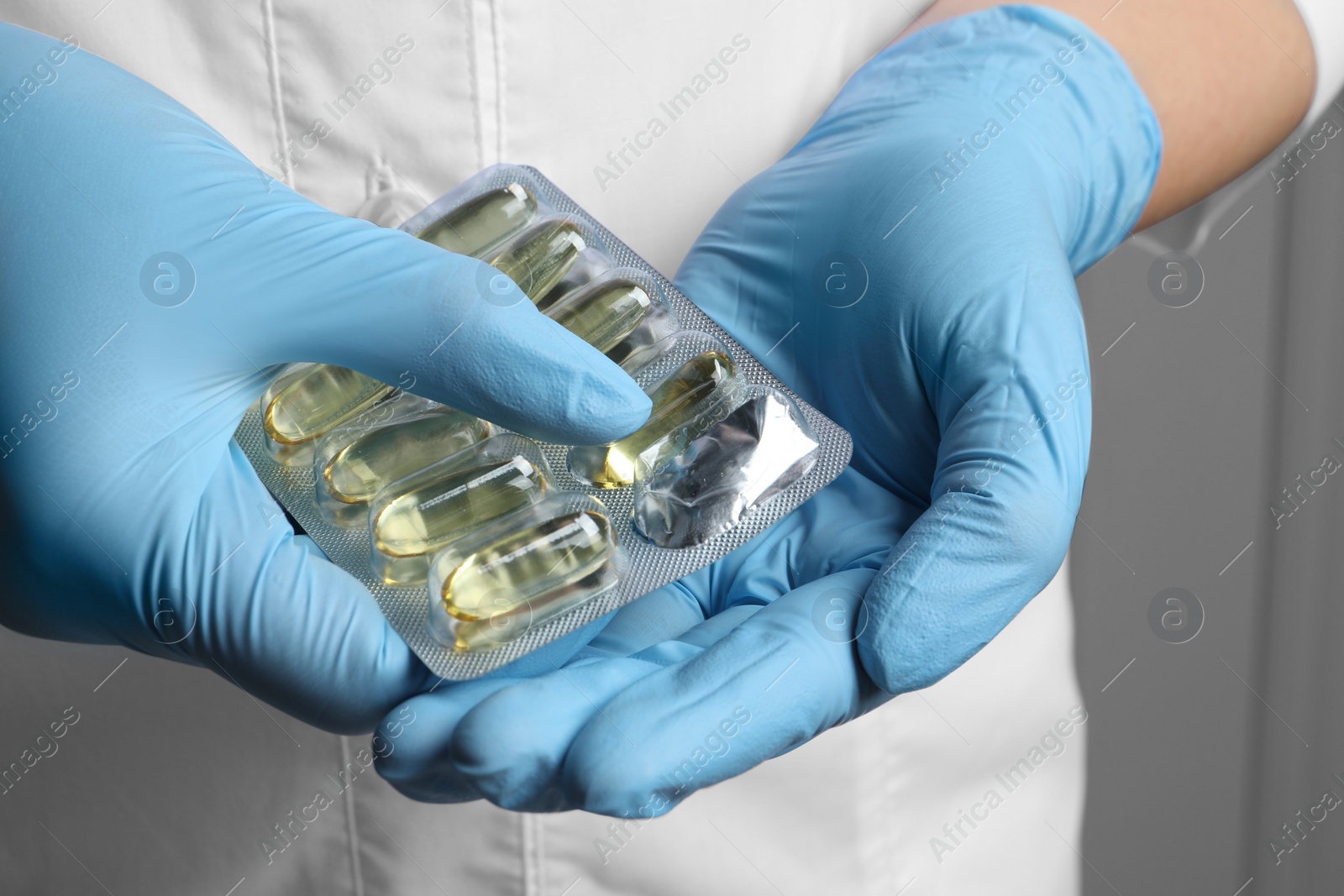 Photo of Doctor taking pill out from blister pack on grey background, closeup