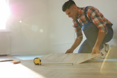 Photo of Professional worker installing new parquet flooring indoors