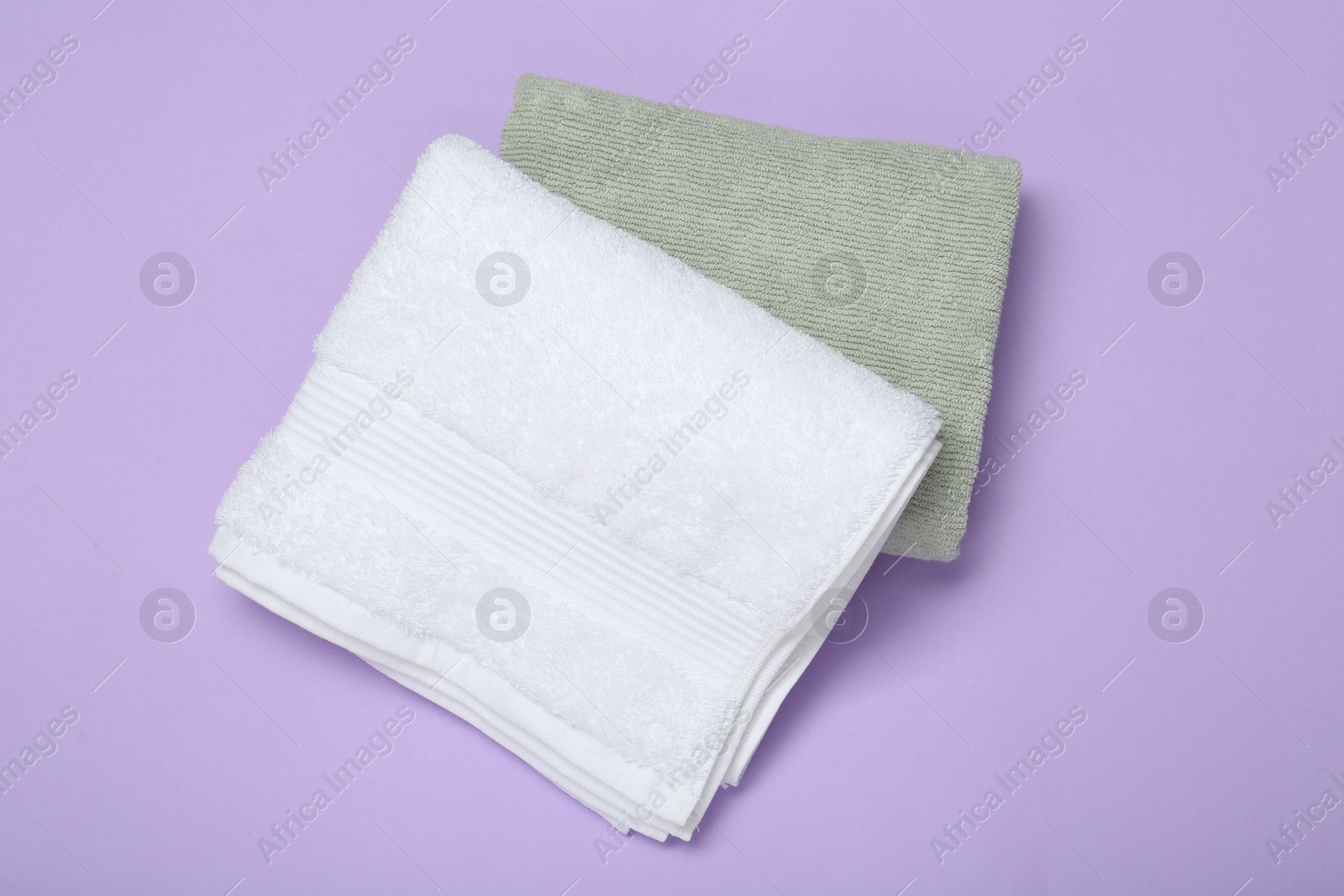 Photo of Different soft towels on violet background, top view