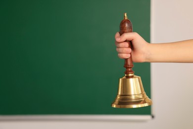 Photo of Pupil with school bell near chalkboard, closeup. Space for text