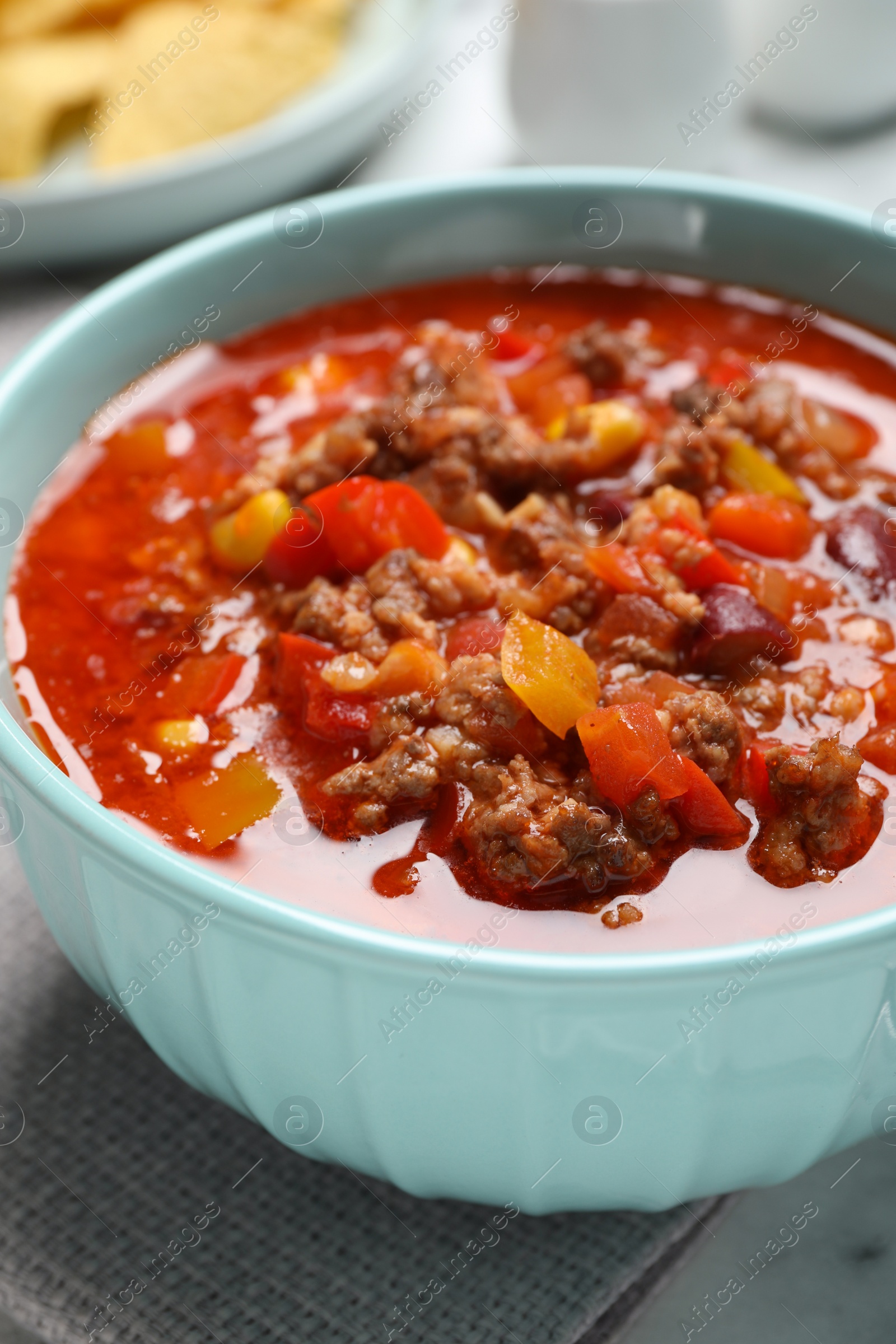 Photo of Bowl with tasty chili con carne on table, closeup