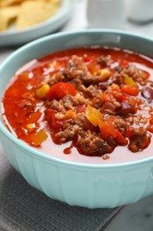 Photo of Bowl with tasty chili con carne on table, closeup