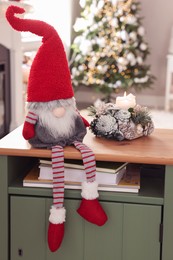 Photo of Cute Christmas gnome on wooden table in room with festive decorations