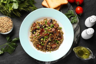 Photo of Delicious lentils with mushrooms, bacon and green onion on grey table, flat lay