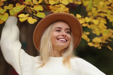 Portrait of happy woman wearing warm sweater in autumn park