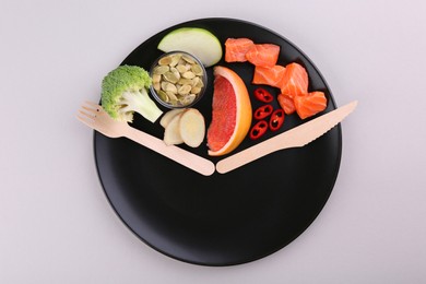 Photo of Metabolism. Plate with different food products and wooden cutlery on light background, top view