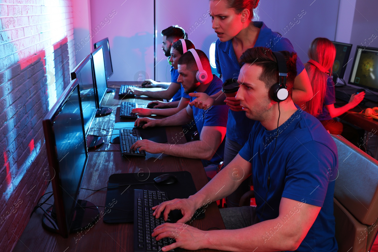 Photo of Young people playing video games on computers indoors. Esports tournament