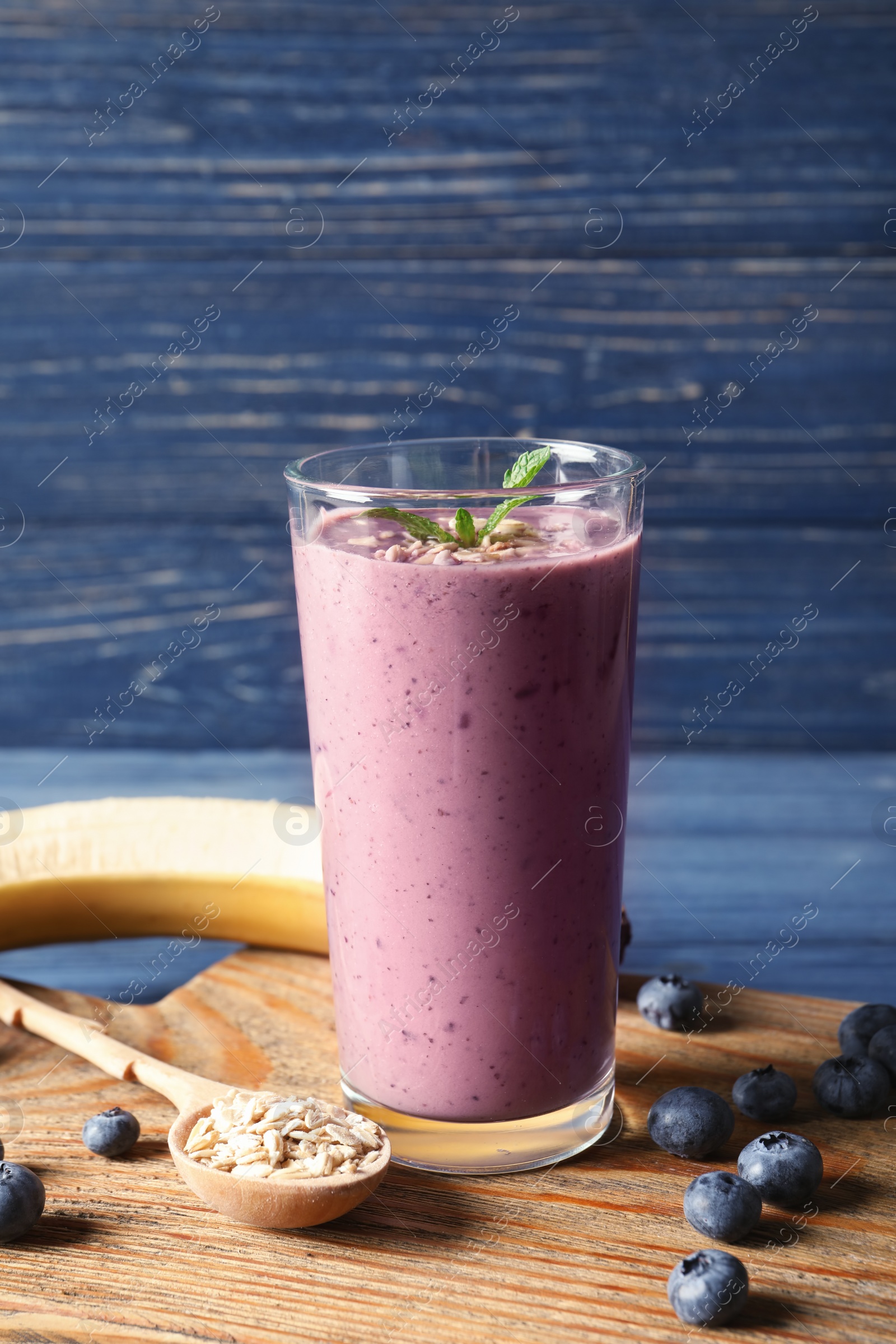 Photo of Glass of blueberry smoothie with oatmeal on wooden table