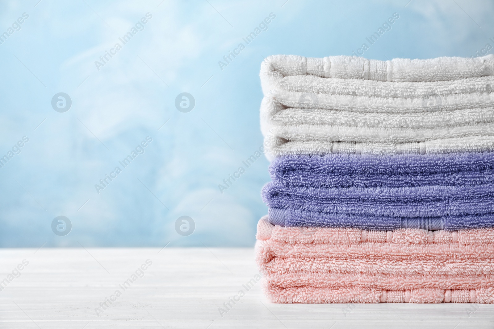 Photo of Stack of soft bath towels on table. Space for text