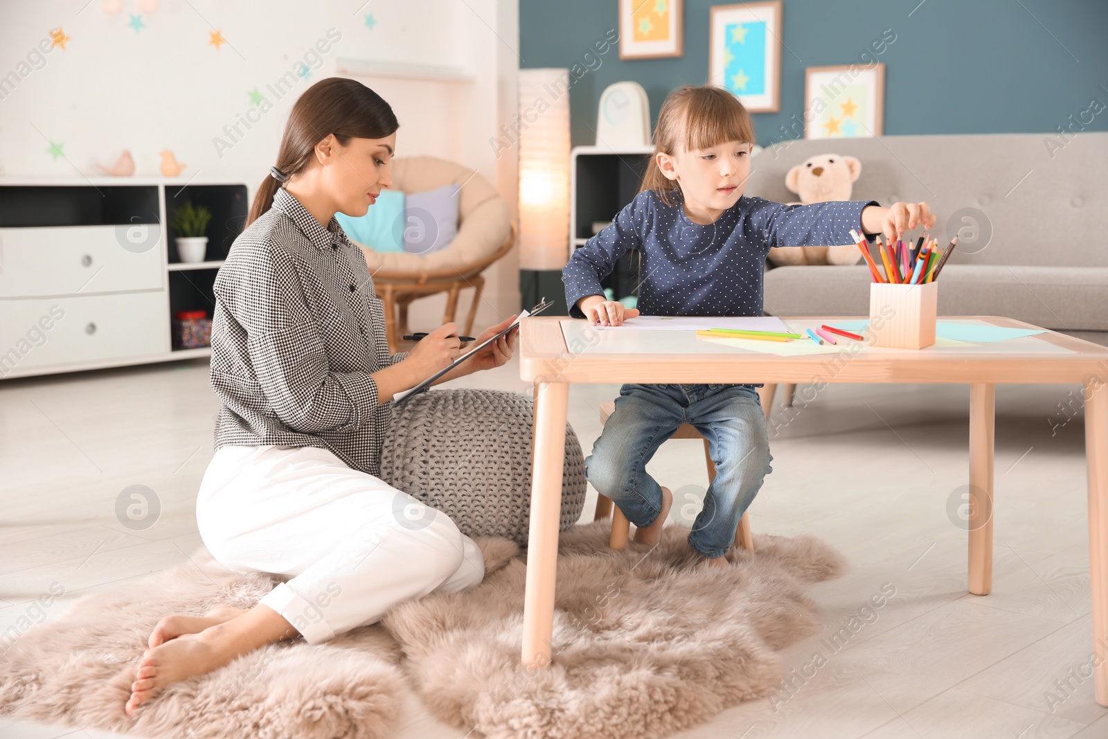 Photo of Female psychologist working with cute little girl in office