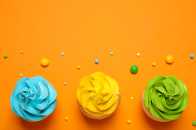 Colorful birthday cupcakes on orange background, flat lay. Space for text