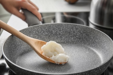 Photo of Woman cooking with coconut oil in frying pan
