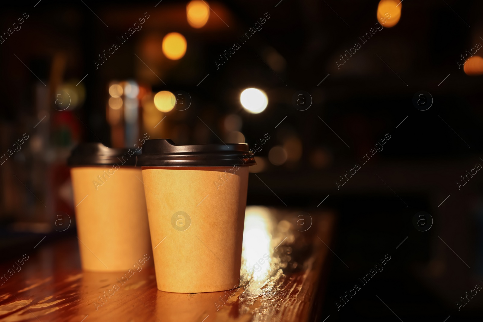 Photo of Paper coffee cups on wooden table in cafe. Space for text