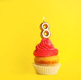 Photo of Birthday cupcake with number eight candle on yellow background, space for text
