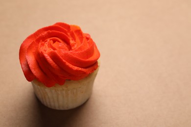 Photo of Delicious cupcake with bright cream on brown background, space for text