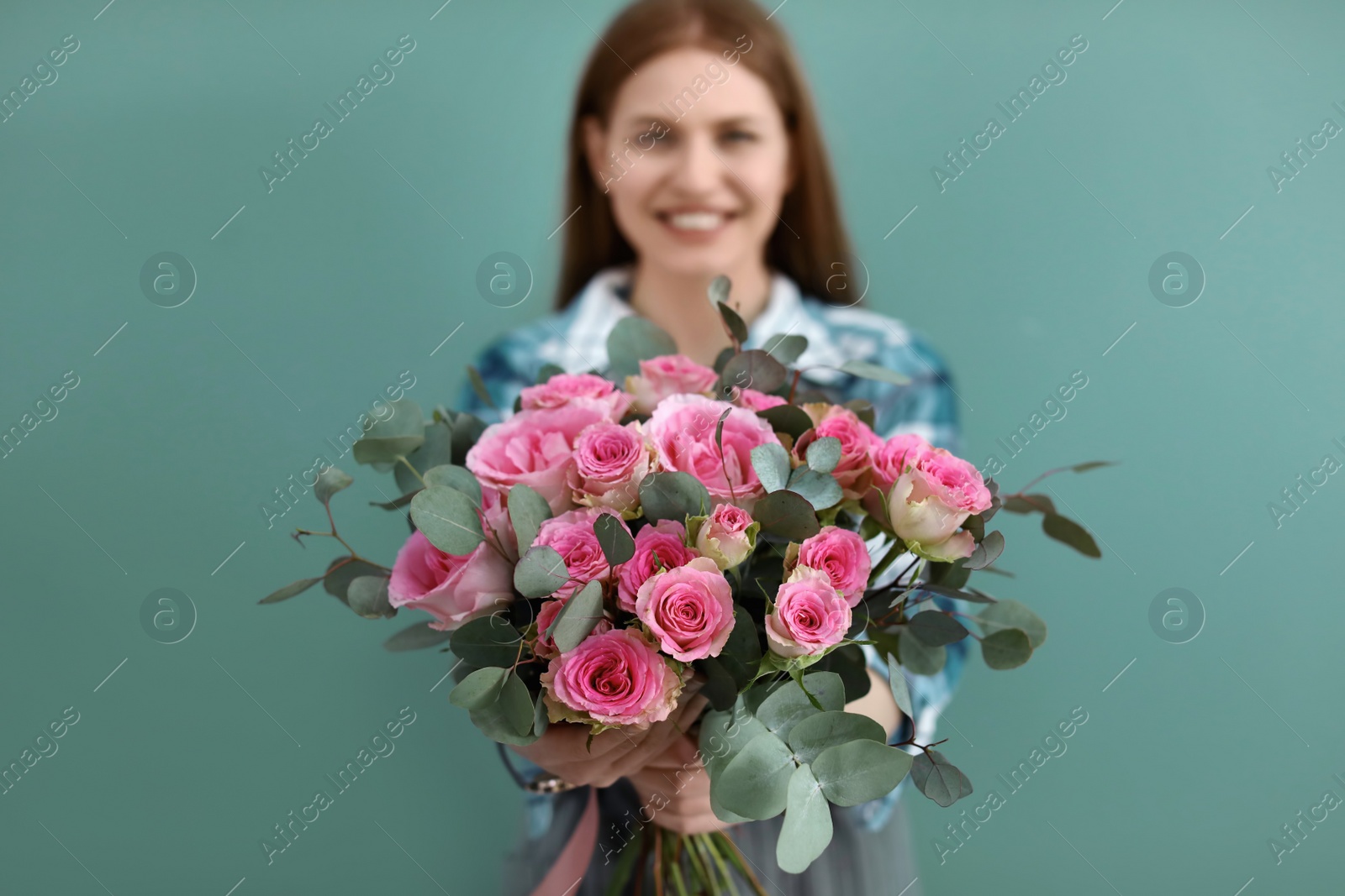 Photo of Female florist holding bouquet of beautiful flowers on color background