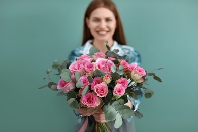 Photo of Female florist holding bouquet of beautiful flowers on color background