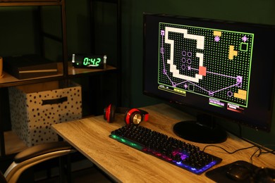 Photo of Modern computer and RGB keyboard on wooden table in dark room