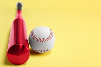 Photo of Baseball bat and ball on yellow background, closeup. Space for text