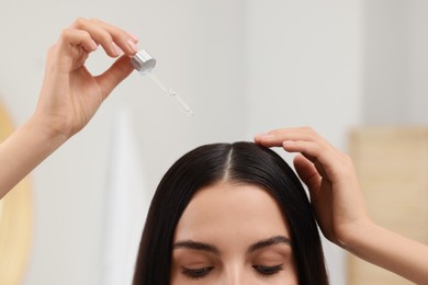 Photo of Woman applying hair serum indoors, closeup. Cosmetic product