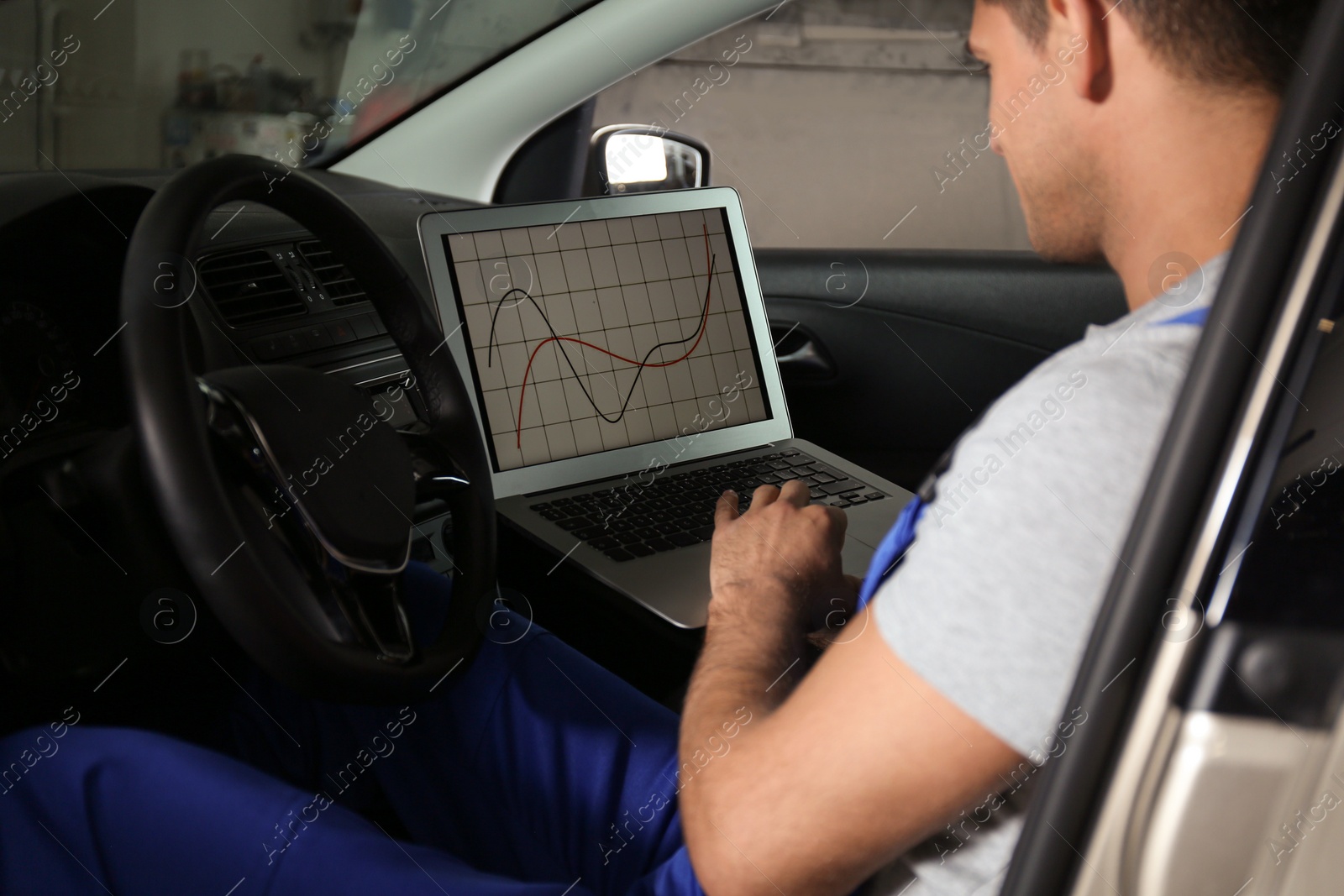 Photo of Mechanic with laptop doing car diagnostic at automobile repair shop