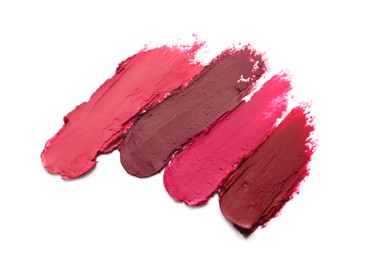 Photo of Smears of beautiful lipsticks on white background, top view