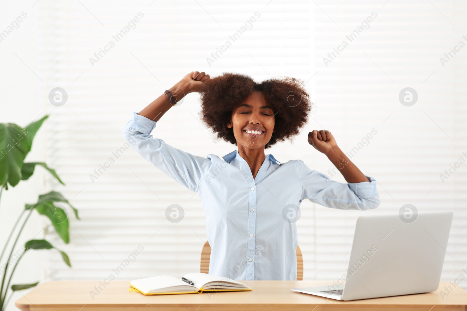 Photo of Smiling African American woman at wooden table indoors
