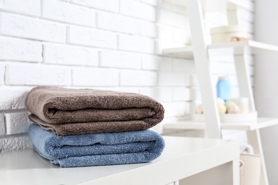 Photo of Stack of fresh towels on table in bathroom. Space for text