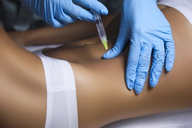 Young woman getting belly injection in salon, closeup