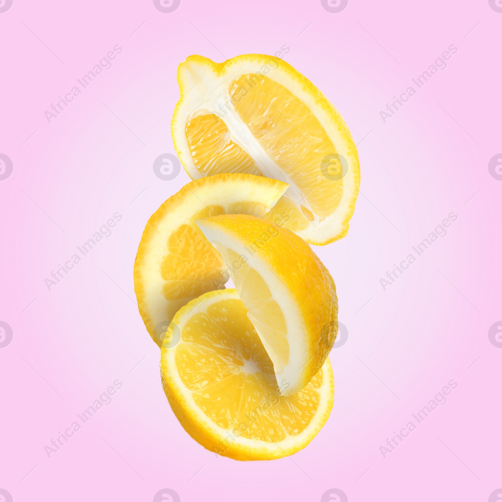 Image of Cut fresh lemons falling on pink background