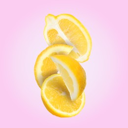 Cut fresh lemons falling on pink background