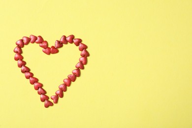 Photo of Heart made of bright sprinkles on yellow background, flat lay. Space for text