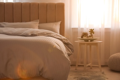 Photo of Comfortable bed with soft blanket near window indoors