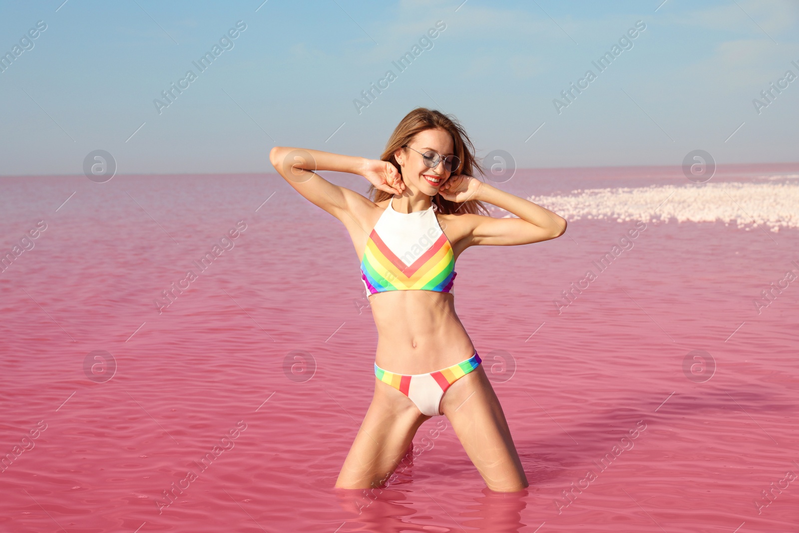 Photo of Beautiful woman posing in pink lake on sunny day