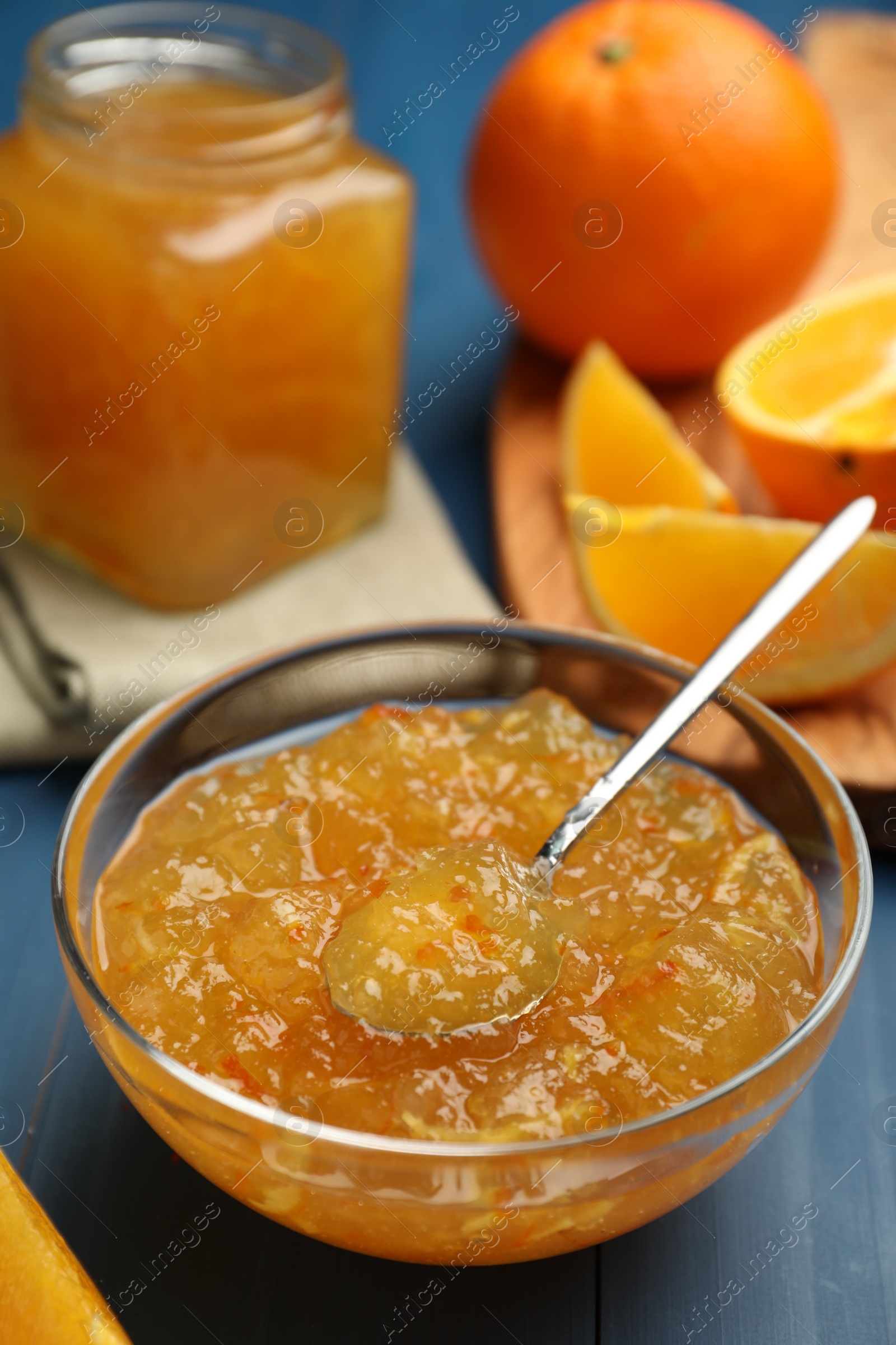 Photo of Delicious orange marmalade in bowl on blue wooden table. Space for text
