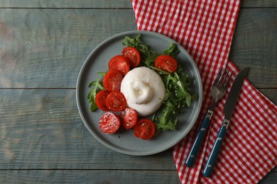 Delicious burrata cheese with tomatoes and arugula served on grey wooden table, flat lay. Space for text