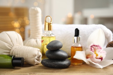 Beautiful spa composition with essential oil and orchid flower on wooden table against blurred lights