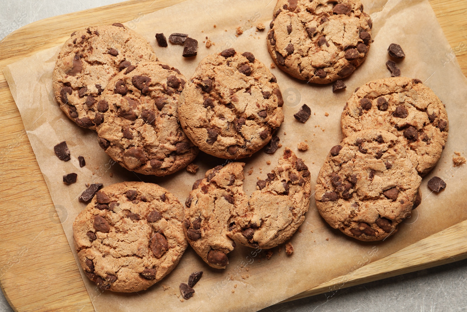 Photo of Many delicious chocolate chip cookies on wooden board, flat lay