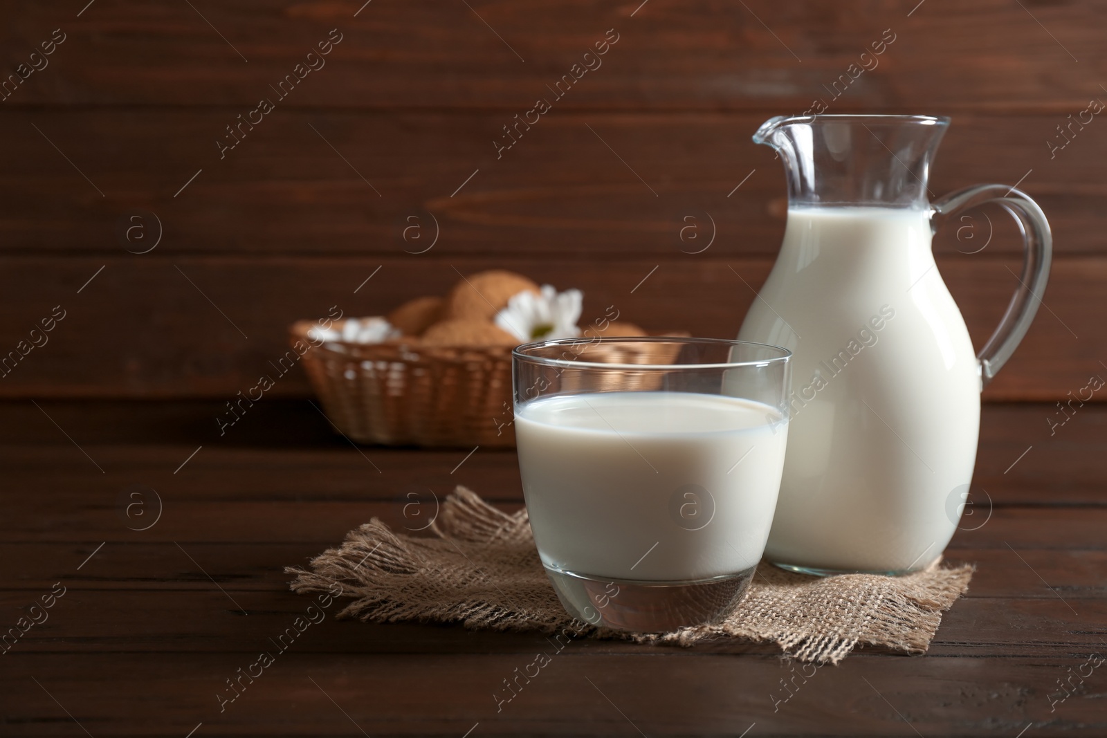 Photo of Glass and jug with milk on wooden table