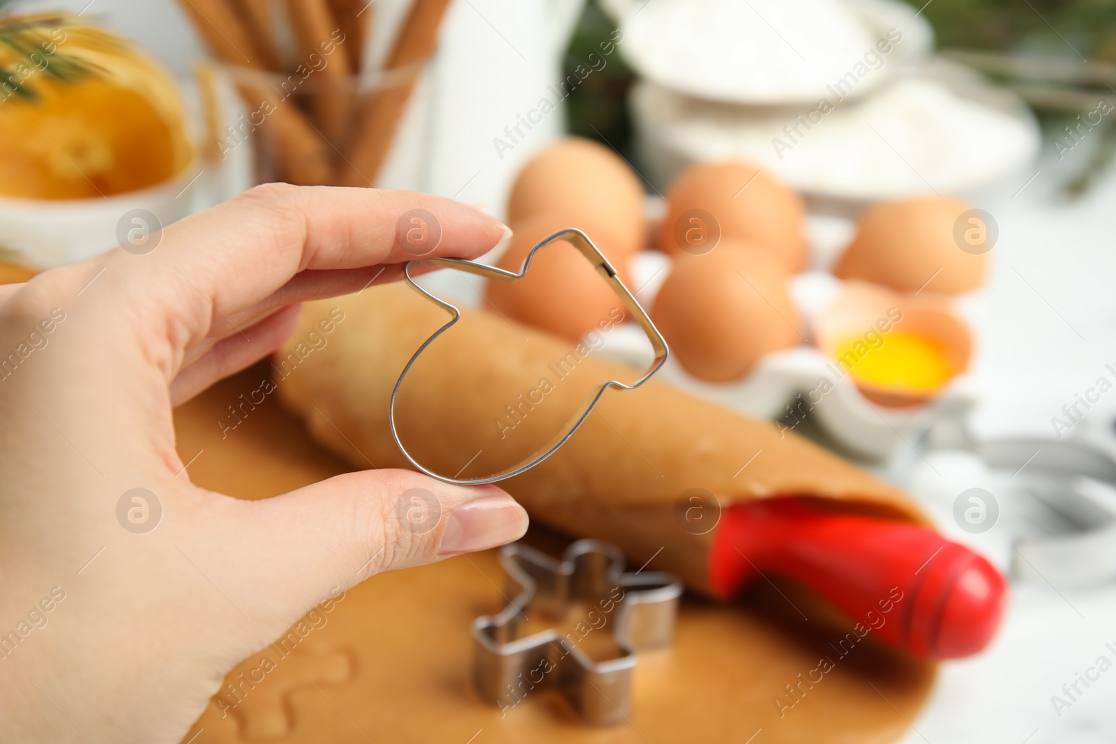 Photo of Woman holding cookie cutter at table, closeup. Christmas biscuits