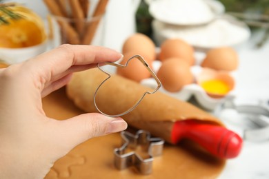 Woman holding cookie cutter at table, closeup. Christmas biscuits